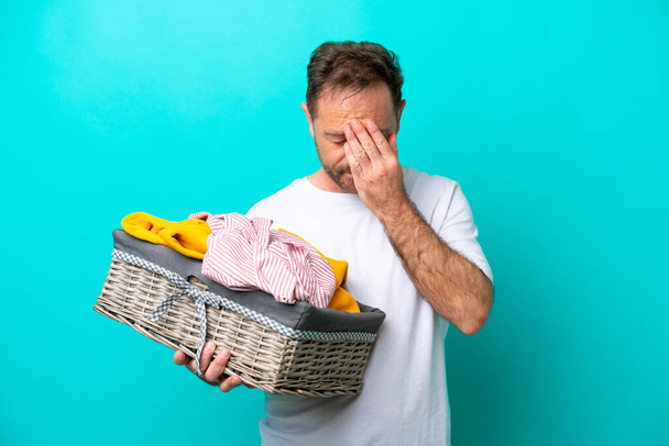 Middle age woman holding a clothes basket isolated on blue background with tired and sick expression - Foto, Imagen