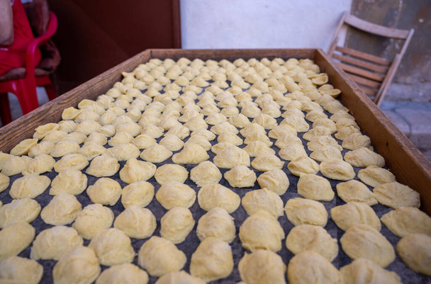 Bari, Puglia, Italy. August 2021. Historic center, close-up photo of freshly prepared orecchiette dried on a fine-meshed wire mesh. Blurred background. - Photo, Image