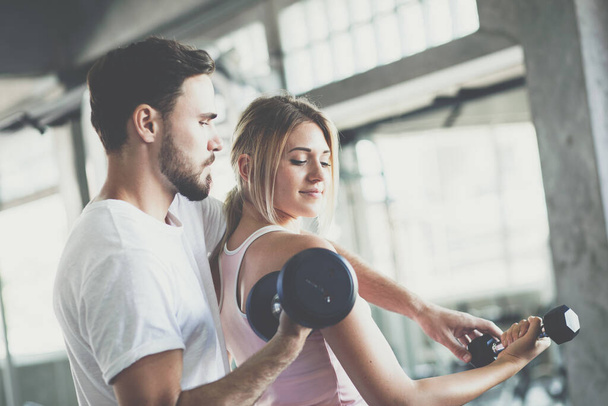 Instructor man teach women lifting up dumbbell in sport gym healthy couple exercise - Foto, imagen