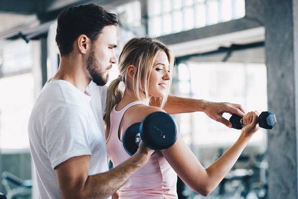 Instructor man teach women lifting up dumbbell in sport gym healthy couple exercise - Photo, Image