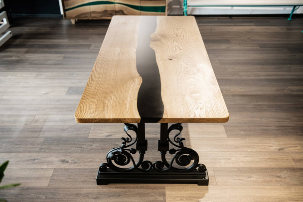 Asztal fából és fekete epoxigyantából kovácsolt fémlábakon - Fotó, kép