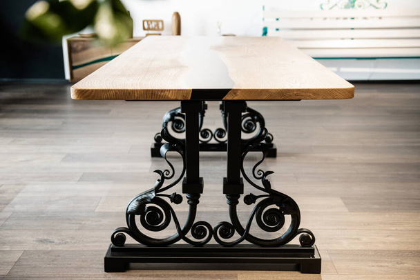 table made of wood and black epoxy resin on wrought metal legs - Fotó, kép