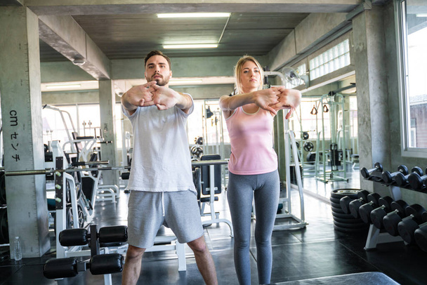 Couple stretch body before exercise in sport gym together private trainer healthy lifestyle - Foto, Bild