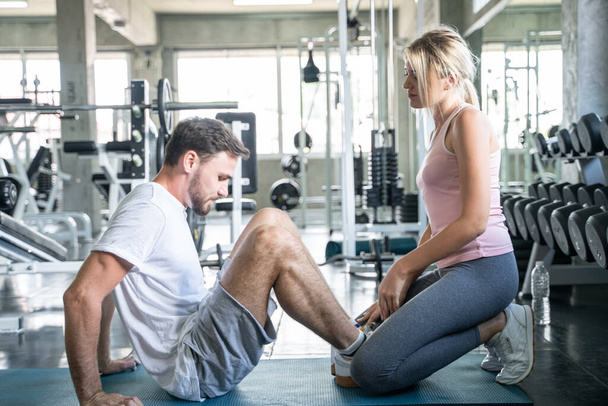 Άνδρες που κάνουν κοιλιακές ασκήσεις fitnest με τις γυναίκες στο γυμναστήριο αθλητισμού fitness και υγιή τρόπο ζωής έννοια - Φωτογραφία, εικόνα