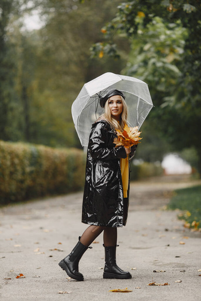 Girl walks. Woman in a black coat. Blonde with a black cap. Lady with umbrella. - Photo, image