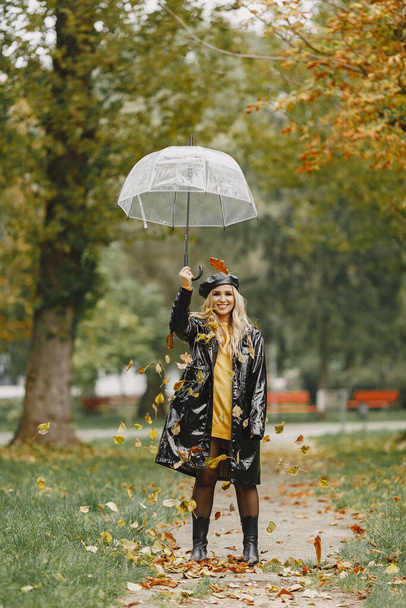 Girl walks. Woman in a black coat. Blonde with a black cap. Lady with umbrella. - Фото, изображение