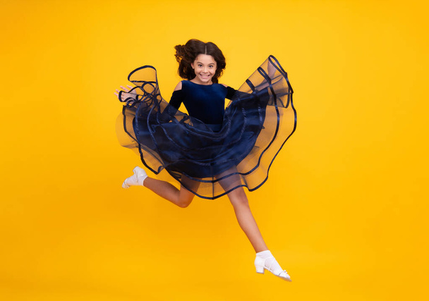 Full length teenager with movement dress. Young teen child with flowing skirt. Teen girl fluttering dress in motion, isolated on yellow. Happy face, positive and smiling emotions of teenager girl - Foto, immagini