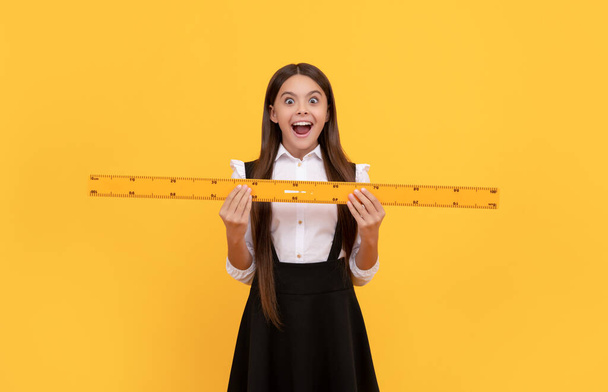 užaslý dospívající dívka ve škole uniforma držet matematika pravítko pro měření, škola. - Fotografie, Obrázek