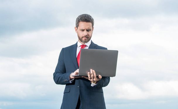 uomo in giacca e cravatta con computer portatile su sfondo cielo. - Foto, immagini