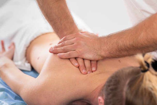 Taking details at professional massage clinic therapist doing a relaxed back massage for a guy he is laying down on the massage table. - Φωτογραφία, εικόνα