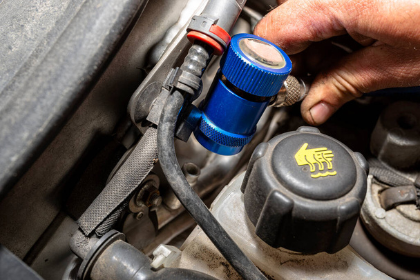 Mechanik vloží rychlorozpínač modře na ventil z klimatizačního systému v autě a naplní chladicí kapalinu R134a. - Fotografie, Obrázek