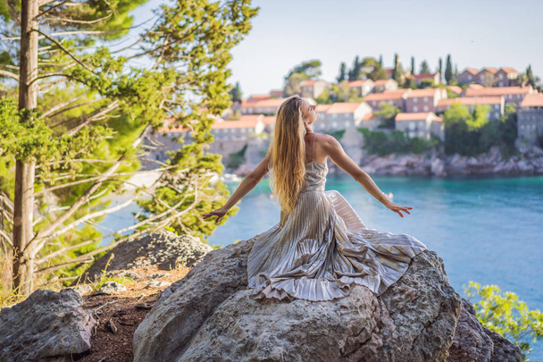 Woman tourist on background of beautiful view of the island of St. Stephen, Sveti Stefan on the Budva Riviera, Budva, Montenegro. Travel to Montenegro concept. - Photo, image