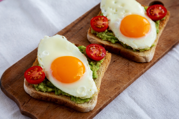 Homemade Healthy Egg, Avocado and Tomato Toast on a rustic wooden board, side view. Close-up. - Fotó, kép