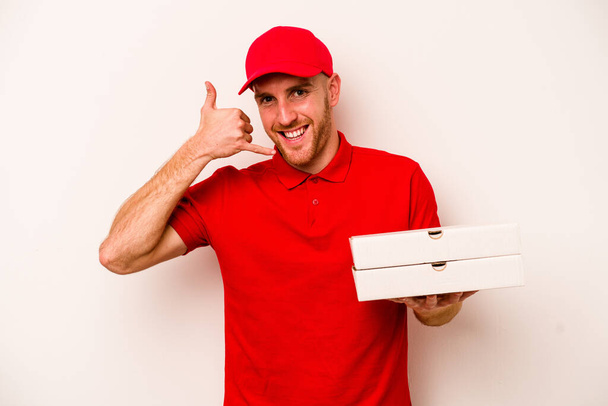 Nuoret toimitus valkoihoinen mies tilalla pizzoja eristetty valkoisella taustalla osoittaa matkapuhelin ele sormin. - Valokuva, kuva
