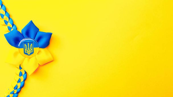 Tło Ukrainy. Ukraiński symbol trójząb kwiat izolowany na żółtym transparencie. Płaskie ułożenie, przestrzeń kopiowania - Zdjęcie, obraz