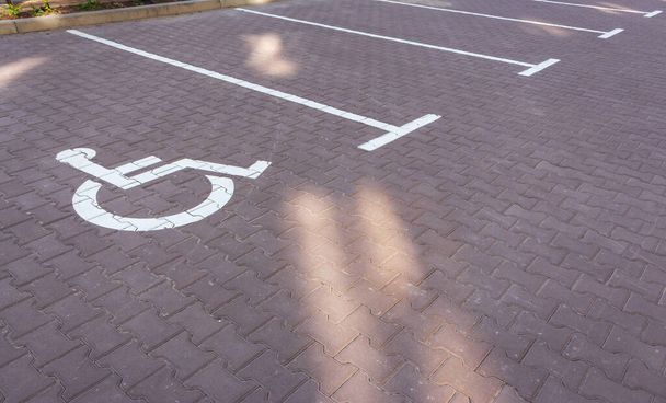 Parkeerplaats voor gehandicapten. Parkeerbord rolstoel op de weg. Parkeerplaats voor gehandicapten. Lege sleuf voor de auto. Stedelijk vervoersconcept. Stadsverkeersconcept. Verkeerstekens voor rolstoelen. - Foto, afbeelding