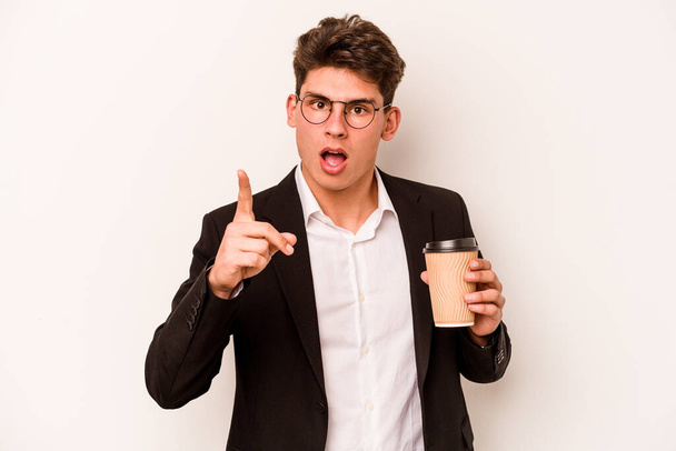 Νεαρός καυκάσιος επιχειρηματίας που κρατάει τον καφέ μακριά απομονωμένο σε λευκό φόντο έχοντας μια ιδέα, μια ιδέα έμπνευσης. - Φωτογραφία, εικόνα