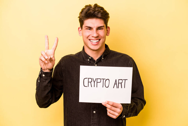 Homem caucasiano jovem segurando cartaz de arte criptografia isolado no fundo amarelo mostrando o número dois com os dedos. - Foto, Imagem
