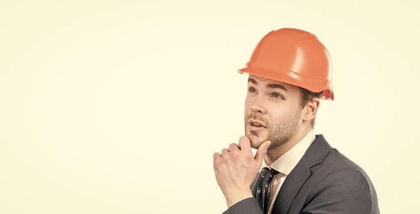 Thoughtful portrait of professional engineering employee in hardhat and suit considering problem isolated on white copy space, consideration. - Photo, Image