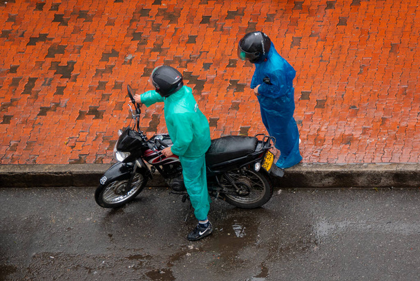 若いヒスパニック系のカップル彼らのプラスチック雨の中でオートバイに乗るスーツ - 写真・画像