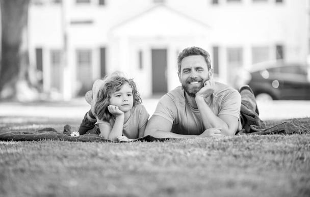 χαρούμενος πατέρας με το παιδί χαλαρώστε μαζί στο πράσινο γρασίδι πάρκο, μητρότητα. - Φωτογραφία, εικόνα