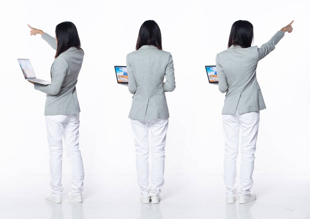 Pełna długość 20-letnia młoda Azjatka nauczycielka biznesu, wskazując palcem w powietrzu, nosić formalne spodnie marynarki buty. Uśmiech Biuro kobieta nosić notatnik laptop na białym tle odizolowany - Zdjęcie, obraz