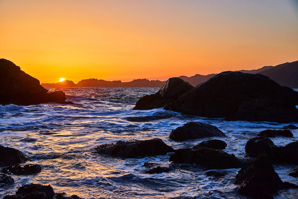 Bild von Sonnenuntergang goldene Stunde am Strand bedeckt mit Meereswellen und Felsen - Foto, Bild