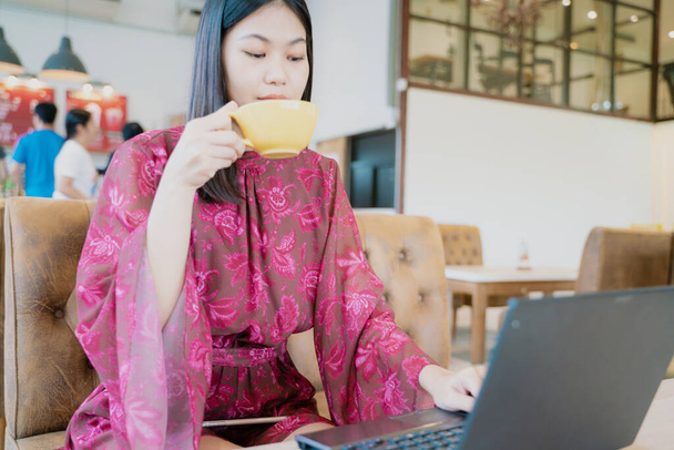 Mooie aziatische vrouwen zitten in restaurant drinken hete koffie gebruik laptop communicatie business - Foto, afbeelding