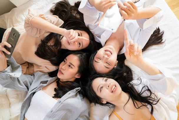 Glücklich fröhliche junge Freundinnen, die Klatsch und Tratsch auf dem Bett liegend mit Blick auf Kamerafreundschaftskonzept aufnehmen - Foto, Bild