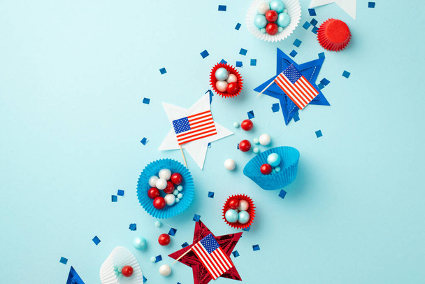 USA Independence Day concept. Bovenaanzicht foto van nationale vlaggen sterren confetti en papier backing mallen met snoepjes op geïsoleerde pastel blauwe achtergrond - Foto, afbeelding