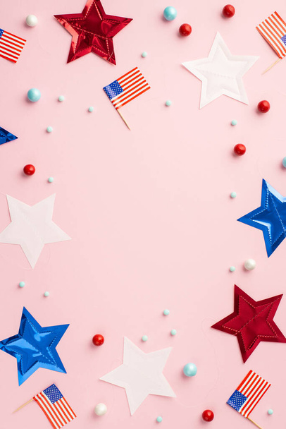 Fourth of July concept. Top view vertical photo of US national flags stars and scattered candies on isolated pastel pink background with empty space in the middle - Photo, Image