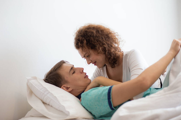 Пара кохання обіймається разом лежачи на білому ліжку після пробудження щасливого ранку
 - Фото, зображення