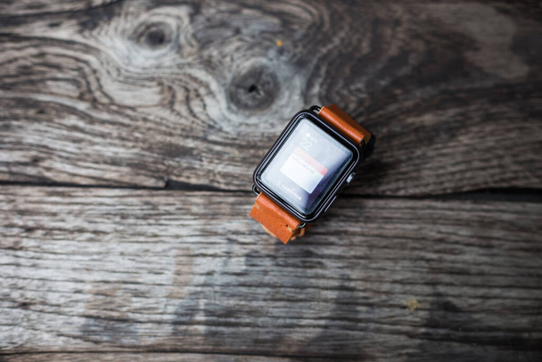 Correa de reloj de cuero marrón con smartwatch artesanía sobre fondo de madera - Foto, Imagen