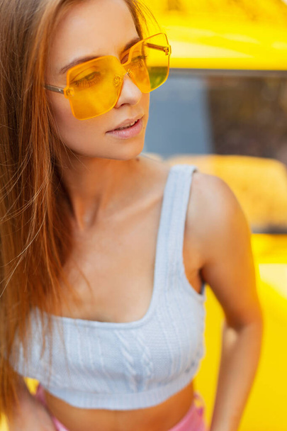 Menina vogue bonita elegante em uma roupa de verão elegante com um top azul de malha e óculos de moda em um fundo colorido brilhante - Foto, Imagem
