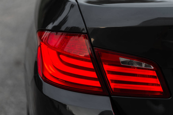 Beautiful modern black car with rear stop lights, close-up. Red headlight LED - 写真・画像