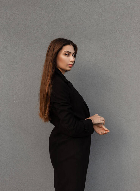 Stylowy piękny biznes młoda kobieta model w modnym czarny płaszcz na szarym tle na ulicy - Zdjęcie, obraz