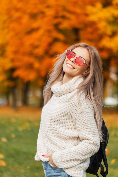Onnellinen kaunis tyttö hymyillen muodikas syksyllä vaatteita villapaita ja farkut reppu - Valokuva, kuva