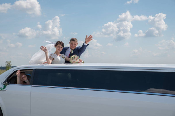 The bride and groom near the wedding limousine. - Foto, Imagen