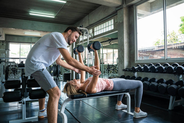 Men teach women practice lifting dumbbell in fitness gym sport activity - Fotoğraf, Görsel