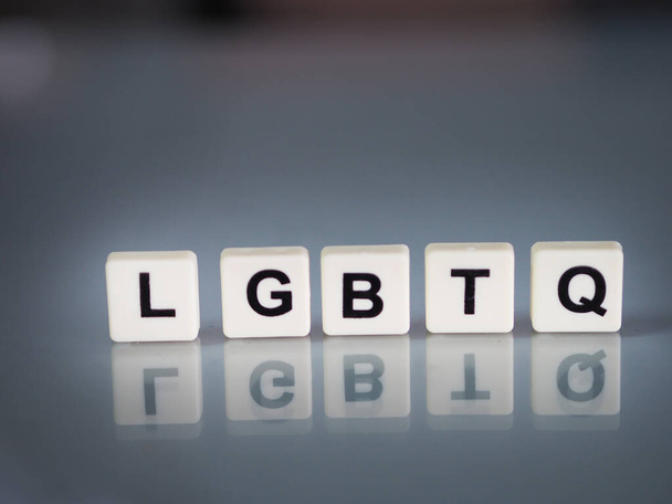 формулировка текста ЛГБТК пластиковыми английскими буквами штампуется на пластиковом листе, отраженном на стеклянном столе - Фото, изображение