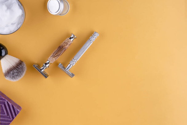 lâminas vintage, escova de barbear, sabão e espuma em uma tigela em um fundo amarelo. Veja acima. Espaço para texto - Foto, Imagem