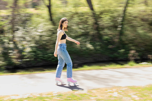 ブルーネット女性スケートで公園でピンクローラースケート - 写真・画像