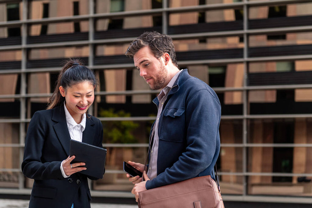young businesswoman showing her tablet to a businessman next to an office building in the financial district, concept of entrepreneurship and business, copy space for text - Foto, immagini