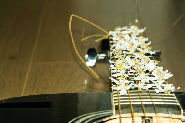 Guitar fingerboard with spring flowers. The long neck is decorated. White flowers - Photo, Image