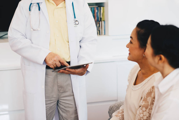 Vanhemmat naiset neuvottelevat lääkärin kanssa sairaudesta klinikalla - Valokuva, kuva