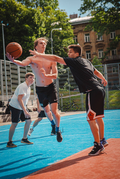 Lwów, Ukraina - 28 maja 2022: mężczyźni grający w koszykówkę na świeżym powietrzu słoneczny letni dzień - Zdjęcie, obraz