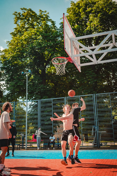 Lviv, Ukraine - May 28, 2022: men playing basketball outdoors sunny summer day - Foto, afbeelding