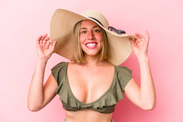 Young caucasian woman going to the beach isolated on pink background - Photo, Image