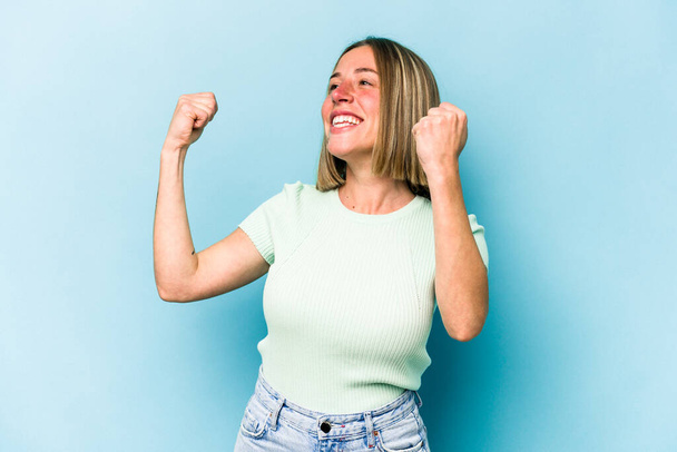 Young caucasian woman isolated on blue background cheering carefree and excited. Victory concept. - Photo, Image