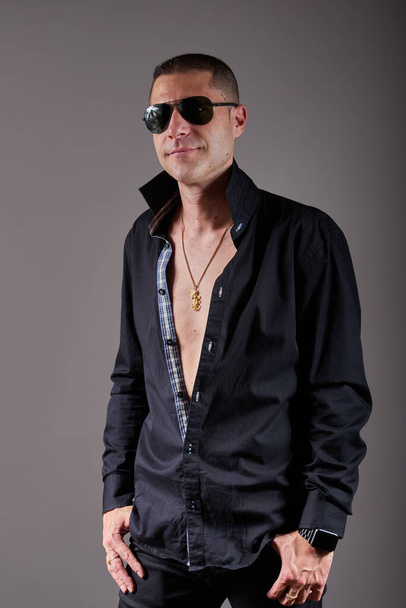 A young man in a black shirt posing in a studio. - Foto, Bild